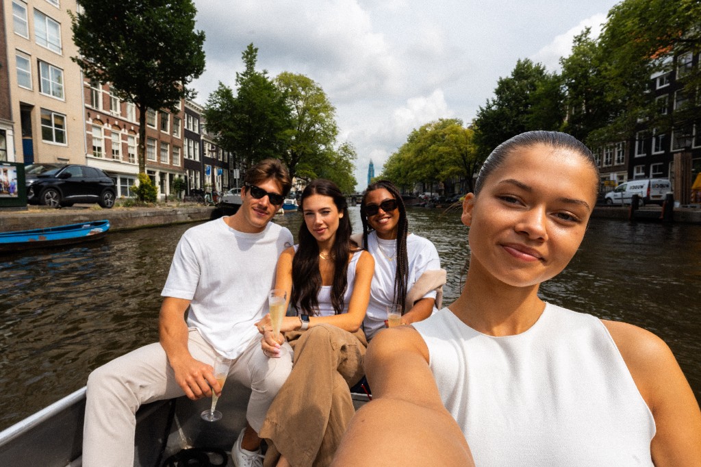 Vrienden nemen een selfie tijdens een boottocht door de Amsterdamse grachten